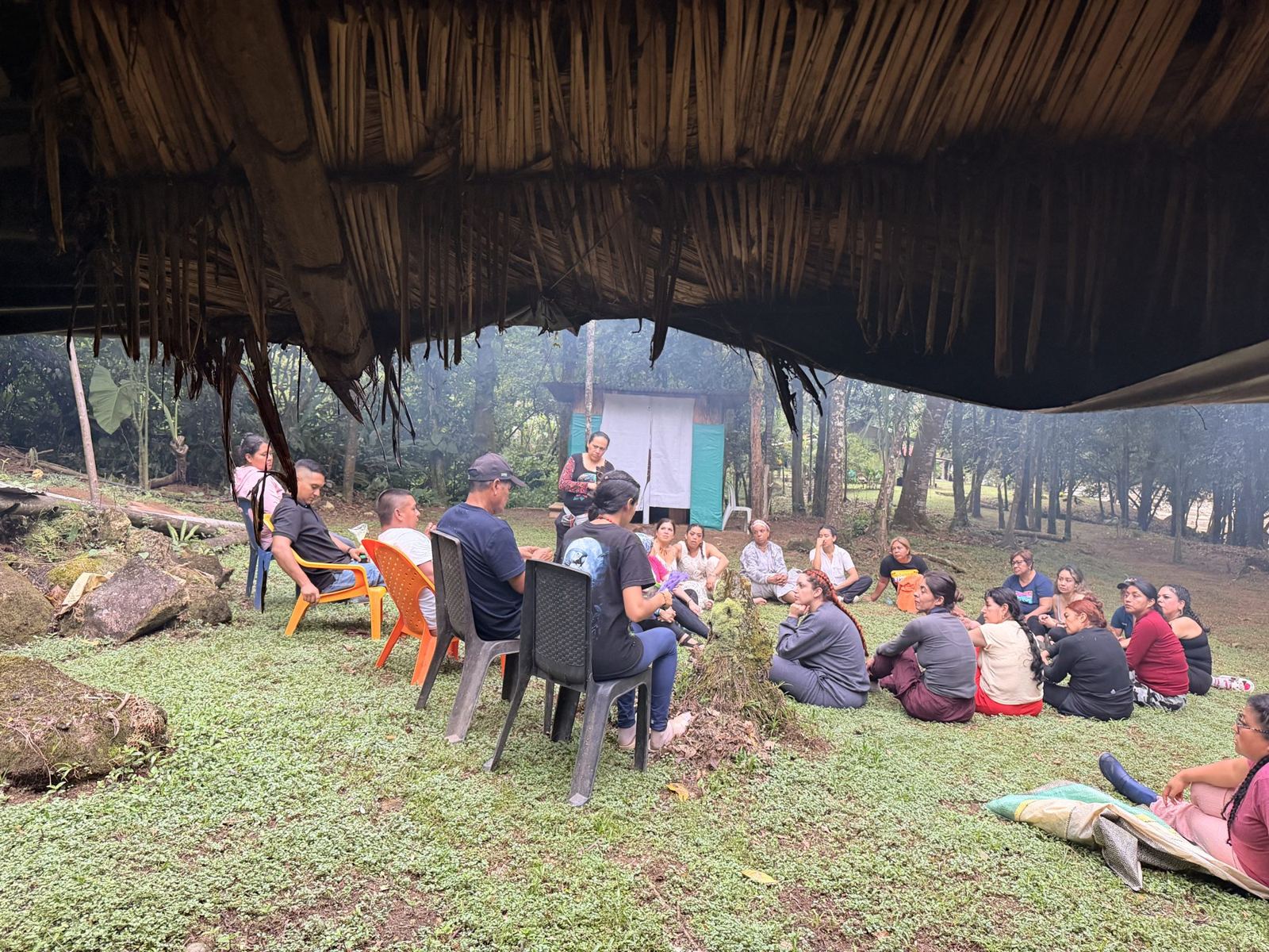 Guests gathered in a circle under a thatched roof